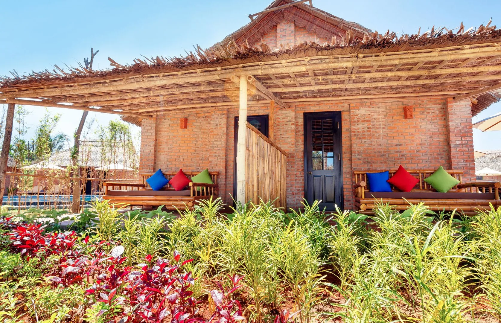 Bungalow sử dụng gạch đỏ, mái lá và nội thất tre gỗ lấy cảm hứng từ nhà truyền thống Việt Nam.