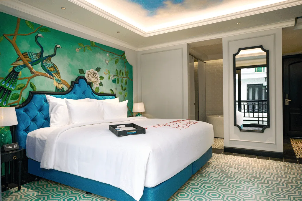 Phòng Premium Pool View mang họa tiết chim công đặc trưng, giường lớn và không gian nghỉ ngơi hiện đại.